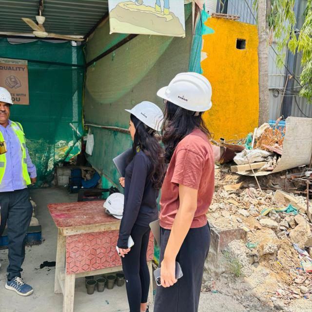 Two volunteers in hard hats talking with a site supervisor in a hi-vis vest
